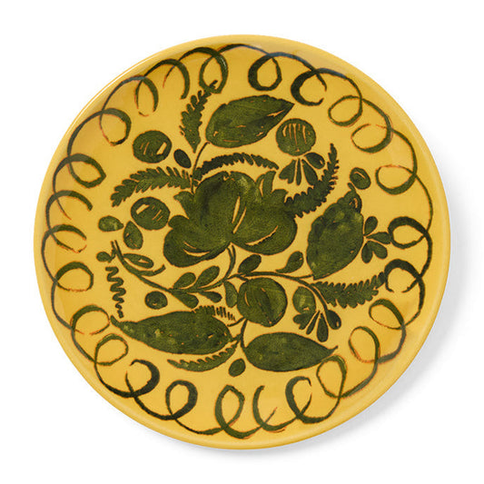 Yellow decorative plate with green floral design on a white background