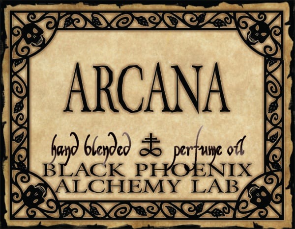 Label for 'Arcana' hand blended perfume oil by Black Phoenix Alchemy Lab with decorative border.