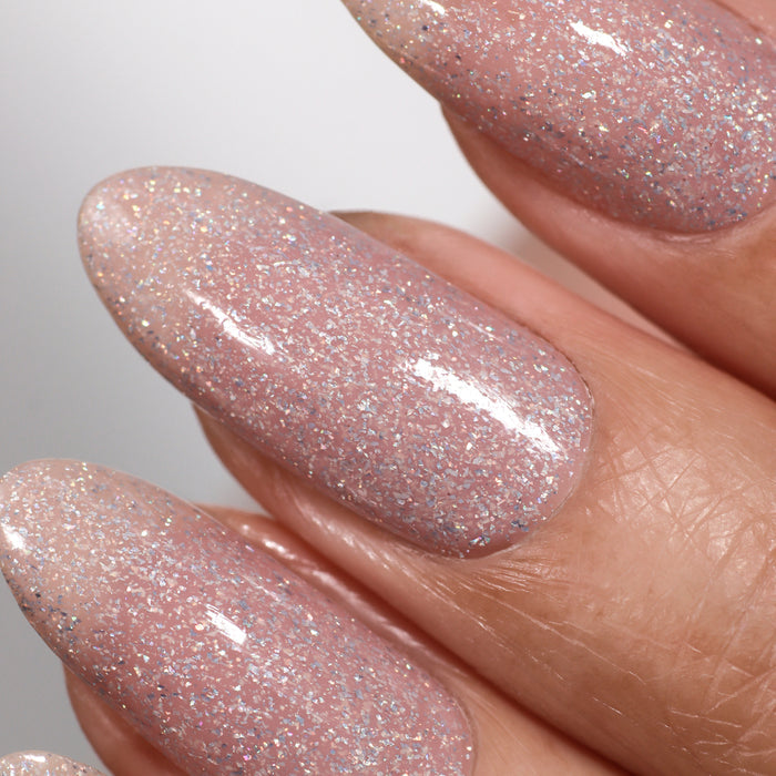 Close-up of fingernails adorned with LONDONTOWN's "Champagne in Bed," a neutral pink glittery nail polish that shimmers with a hint of holographic sparkle.