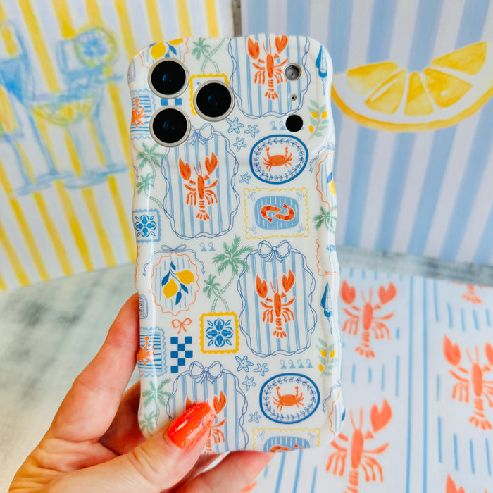 Trendy blue and white wavy iPhone case featuring a nautical collage of orange lobsters, crabs, lemons, and palm trees with a high-gloss finish.