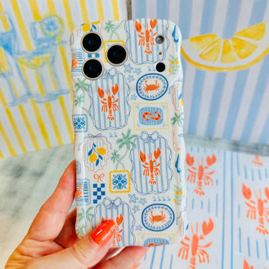 Trendy blue and white wavy iPhone case featuring a nautical collage of orange lobsters, crabs, lemons, and palm trees with a high-gloss finish.