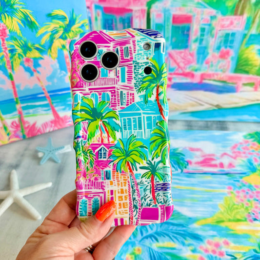 Trendy wavy iPhone case featuring a vibrant tropical resort scene with pink villas and green palm trees with a high-gloss finish.