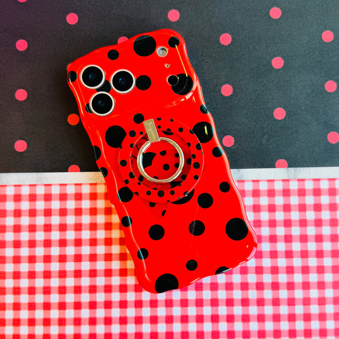 Bright red wavy iPhone case with large black polka dots and a central ladybug featuring a white heart on its wing.
