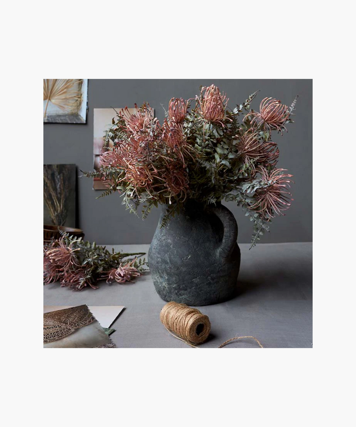 A Leucospermum bush with green and pink leaves in a grey vase , intended for home decor purposes. | SW Home