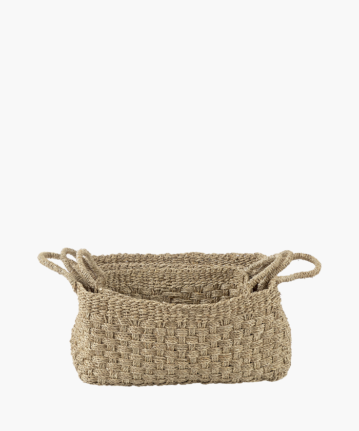 Three rectangular seagrass woven baskets in various sizes with two looped handles, made of natural fibers in a textured, checkerboard pattern. The tone is earthy and rustic. | Wildwood Home Co.