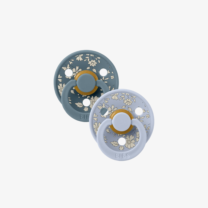 Two blue floral-patterned pacifiers on a white background