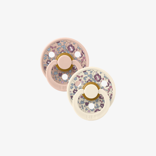 Two floral-patterned baby pacifiers on a white background