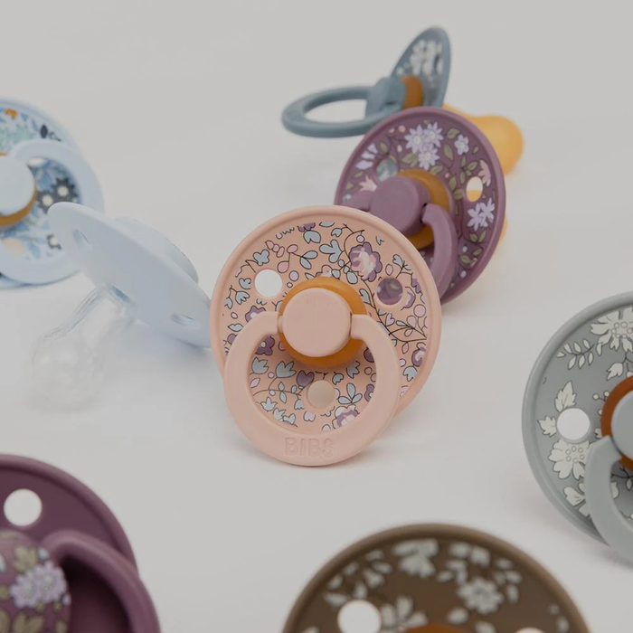 Colorful baby pacifiers with floral patterns on a white background