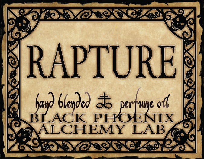Advertisement for 'Rapture' hand blended perfume oil by Black Phoenix Alchemy Lab with decorative border and text.
