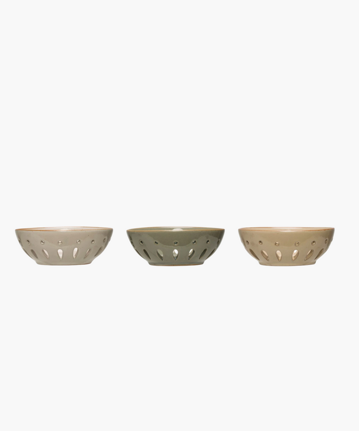 Side profile of three colanders in muted beige and gray tones are evenly spaced in a row. Each has a sleek, modern design with decorative cutout patterns. | Wildwood Home Co.